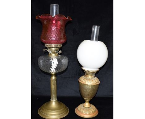 AN EDWARDIAN TWIN BURNER OIL LAMP  with cranberry glass shade and clear glass reservoir, on reeded column with circular foot,