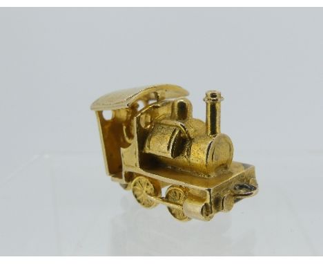 A 9ct yellow gold charm, in the form of a steam engine, the hinged cab opening to reveal driver, 4.9g, together with a gold p