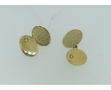 A pair of 9ct yellow gold oval Cufflinks, one side engine turned, the other plain with a small diamond point, chain between, 