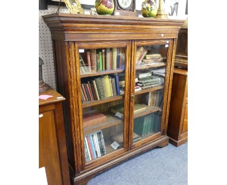 A late Victorian oak Bookcase, the rectangular top with moulded cornice above two glazed doors enclosing adjustable shelves o