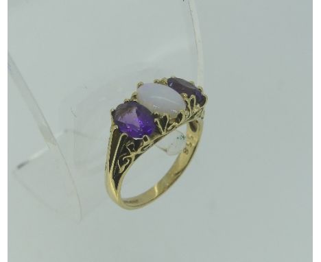 An opal and amethyst three stone Ring, the central oval opal with a facetted oval amethyst on either side, in a scrolling gal