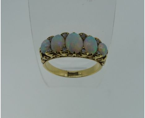 A graduated five stone oval opal Ring, each with two rose cut diamonds set vertically between, in a carved gallery, the shank