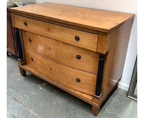 A 19th century satinwood chest of drawers, the lower two drawers bowfronted, flanked by ebonised ionic columns, on square tap