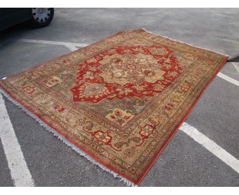 A Middle Eastern Tassled Carpet, with central medallion in the Indian manner, allover floral motifs on red and cream ground, 