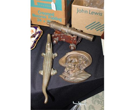 Brass cannon on a wooden trolley, brass nutcracker in the form of a crocodile, brass mask depicting a moustached gentleman (3