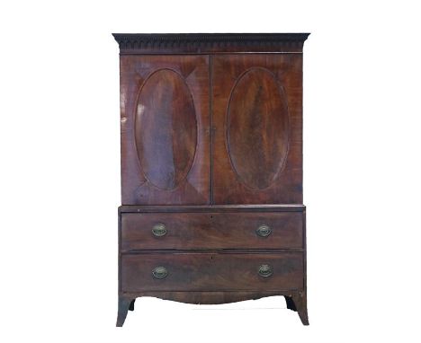 Regency mahogany linen press, the dental cornice above drop finials and a pair of doors with oval panels enclosing the slides