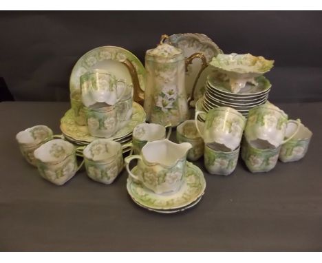 An Austrian ceramic teaset decorated with flowers on a green ground comprising a coffee pot, milk jug, tea plates, serving pl