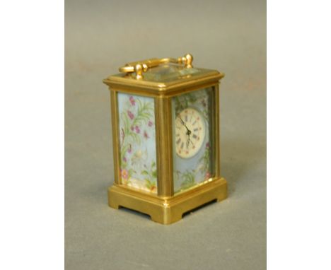 A miniature brass carriage clock with inset porcelain panels decorated with wading birds amongst reeds and flowers, 2½'' high
