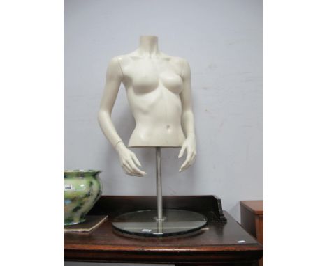A Female Form Shop Mannequin, removable arms on an adjustable heavy glass base, approximately 90cm high.