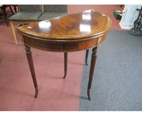 A XX Century Mahogany Demi Lune Fold Over Card Table, with a cross banded top, green leather inserts on turned and reeded leg