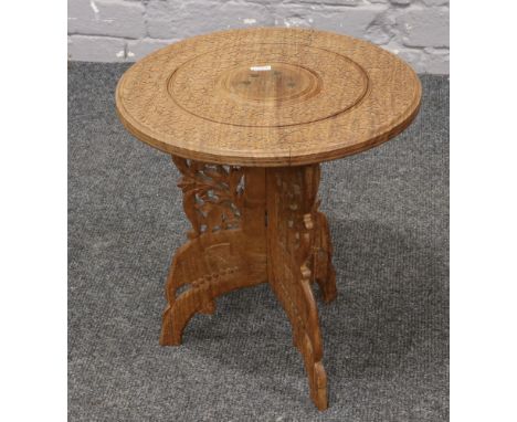 An Indian hardwood occasional&nbsp; table with carved decoration and brass inlaid top.