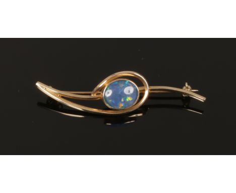 A vintage 9ct gold scrolling openwork bar brooch set with a large ovoid opal doublet.&nbsp;