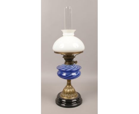A Victorian brass based oil lamp with striped blue glass font.Condition report intended as a guide only.Chip to shade.