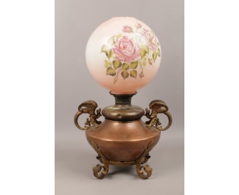 A large Victorian brass and copper based oil lamp with painted glass shade. Having twin dragon moulded handles and raised on 