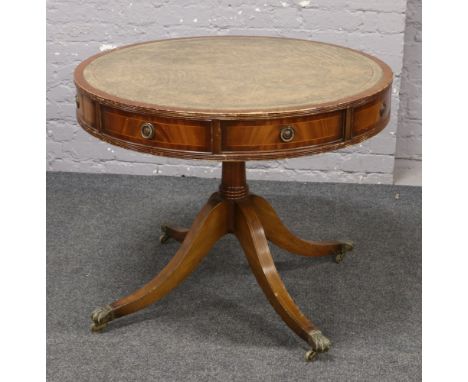 Rotating leather inset drum table raised on brass lion paw castered feet.