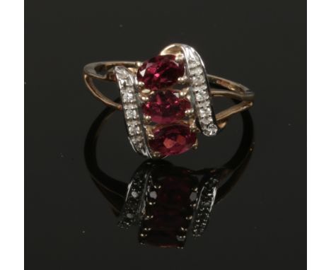 A 9ct gold dress ring diagonally set with three garnets on split shoulders. Size R 1/2.