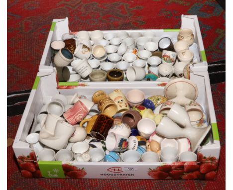 Two boxes of mostly ceramic egg cups including studio pottery, Wedgwood Peter Rabbit, novelty and double examples.