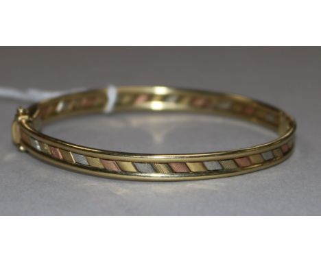 A 9ct three-colour gold hollow hinged bangle, 9.9gr