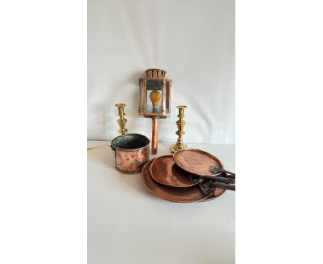 Copper lantern with glass panels and wooden handle, flanked by two brass candlesticks. The lot includes four copper pans and 