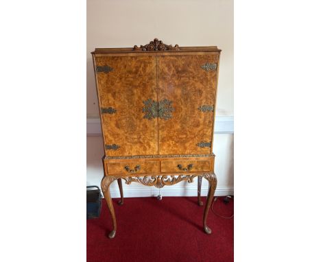 Burr walnut drinks cabinet features ornate brass handles and hinges, cabriole legs, and an interior with a mirrored back and 