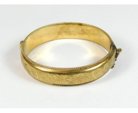 GOLD BANGLE. A 1960s, 9ct. gold hinged bangle, engraved all round. Approx. 24g.  Please note that all items in this auction a