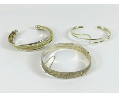 SILVER BRACELETS. A silver bark-textured bangle & two silver torque-type bracelets.  Please note that all items in this aucti