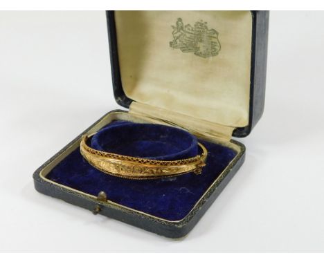 GOLD BANGLE. A 9ct. gold hinged bangle with an engraved front. Approx. 7.3g.  Please note that all items in this auction are 