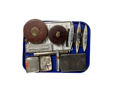 Two vintage leather cased tape measures, a tin containing trophy badges, an oversized Zippo style lighter, an album containin