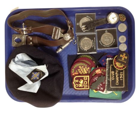 A tray containing commemorative crowns and coins, a gent's Timex wristwatch, girl guides, a leather belt with whistle, a neck