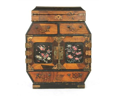 A late 19th century Japanese table cabinet, with parquetry panels on lacquer work, the two cupboard doors to the front inlaid