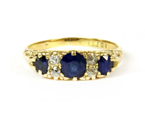 A three stone sapphire ring, the central round faceted sapphire flanked on each side by a column of two round faceted diamond