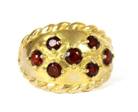 A 9ct gold bombe ring, claw set with garnets to twisted wire guards, 4.81g, size M