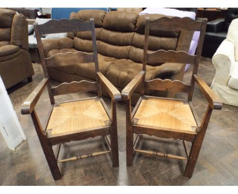Pair of heavy oak ladder back style carver chairs with rush seats