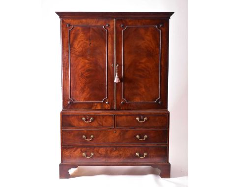 A George III mahogany linen press, converted to a wardrobe, the shaped cornice above two flame-figured, razor-blade panelled 