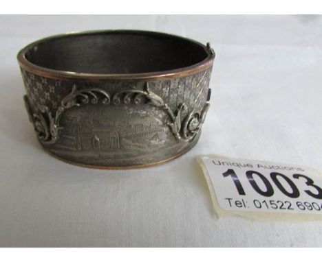 An engraved white and yellow metal bangle
