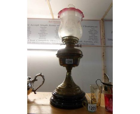 A brass oil lamp on pot base and with etched shade