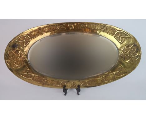A GLASGOW SCHOOL OF ARTS AND CRAFTS BRASS FRAMED MIRROR of oval form with celtic knotwork decoration, 85cm x 41cm Condition R