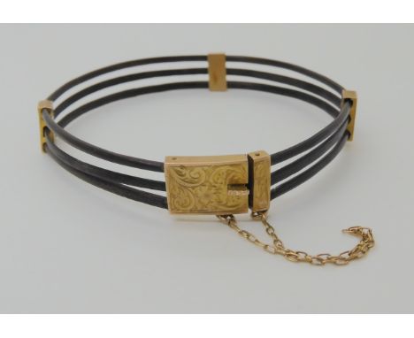 AN ELEPHANT HAIR BANGLE The three strands held together with three 9ct gold engraved spacers and a 9ct hallmarked box clasp. 