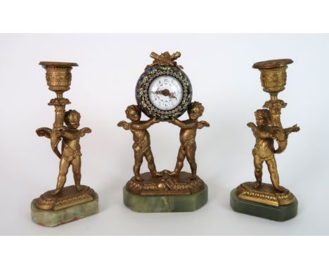 A FRENCH CHAMPLEVE ENAMEL TIMEPIECE modelled as a pair of cherubs supporting the ball shaped dial, with painted Arabic number