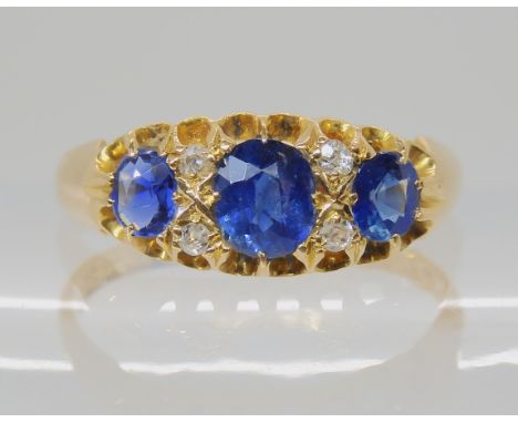 A SAPPHIRE AND DIAMOND THREE STONE RING the largest sapphire measures approx 5mm x 4mm x 2.9mm, flanked by two smaller exampl