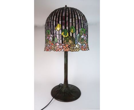 A LARGE LEADED AND STAINED GLASS TABLE LAMP the metal tree trunk body supporting a flower decorated domed shade, 98cm high Co