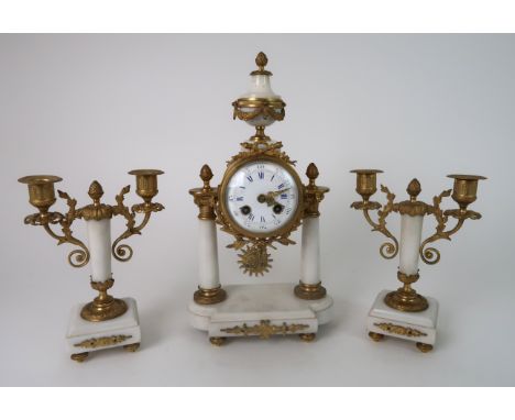 A FRENCH ALABASTER AND ORMOLU MOUNTED CLOCK GARNITURE the drum head clock supported by two columns and with a urn finial, wit