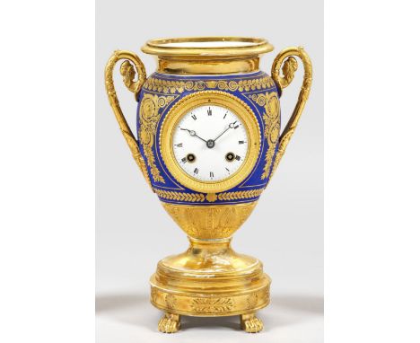 Empire-VasenuhrPorzellan mit flächendeckendem puderblauen Fond sowie reicher, teilw. radierter Goldstaffage. Über ovalem Prof