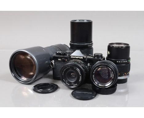 A Black Olympus OM-2 SLR Camera and OM Lenses, serial no 506367, body F-G, extensive edge brassing, shutter working, meter re