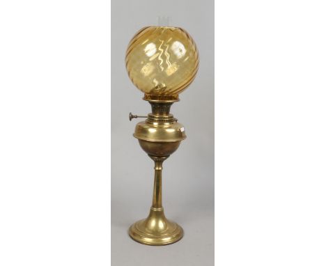 A Victorian brass based oil lamp with amber swirl glass shade.