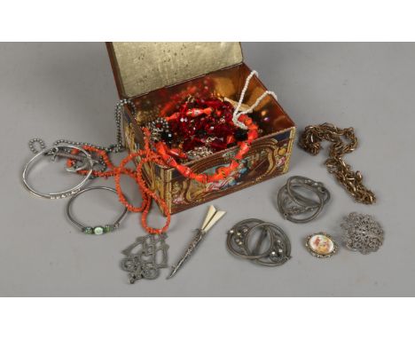 A vintage biscuit tin with boucher style decoration containing costume jewellery beads, brooches etc.