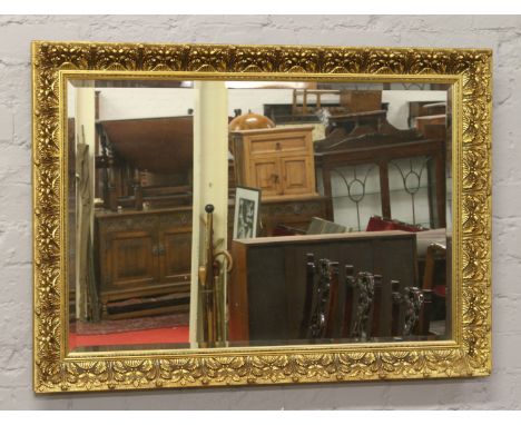 A ornate gilt framed bevel edge wall mirror.