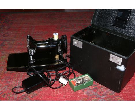 A portable Singer electric sewing machine model number 221K complete with instruction manual and accessories.