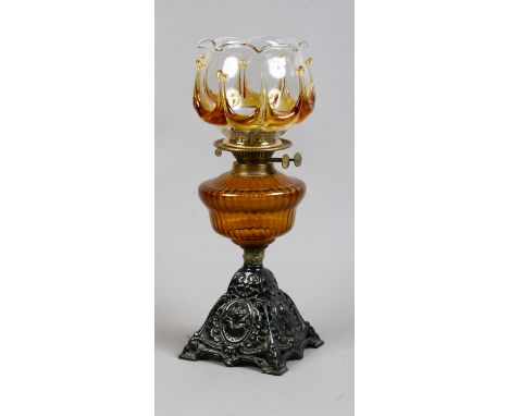A Victorian cast iron based oil lamp with decorative two tone glass shade raised over amber glass font.