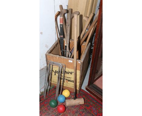 A vintage tea chest and contents of croquet mallets, hoops and balls, along with hockey sticks etc.